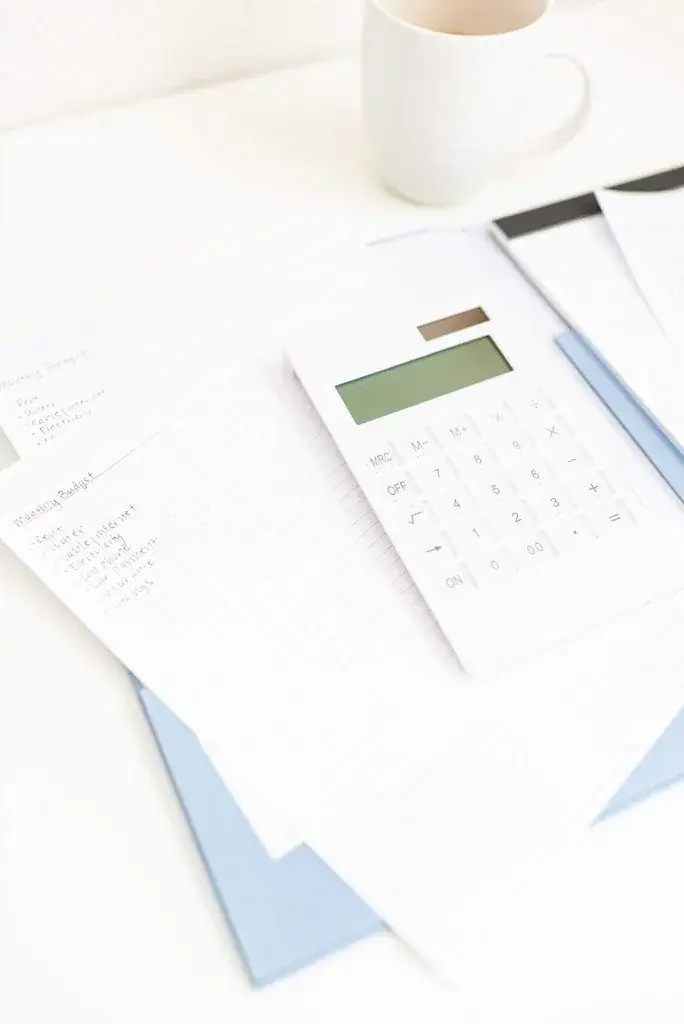 Calculator and financial papers beside a cup of coffee