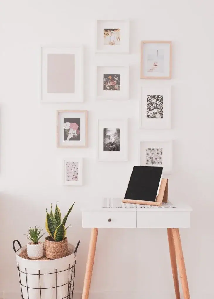 Minimal white desk with laptop, wall art, and plants