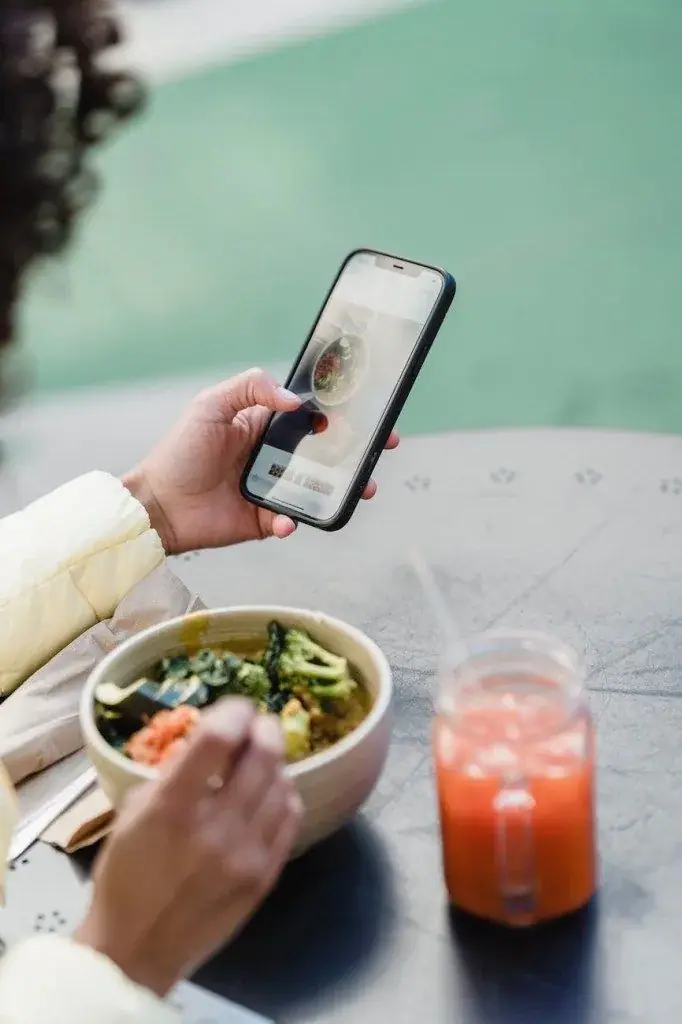 Person eating a salad while looking at a smartphone