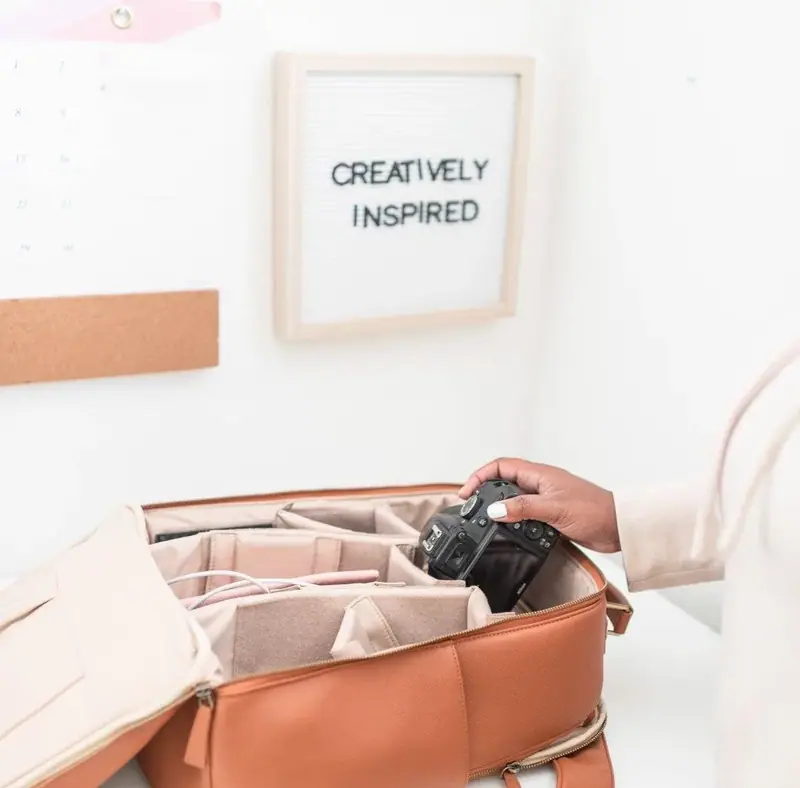 Camera in an open bag beneath a sign reading “Creatively Inspired”