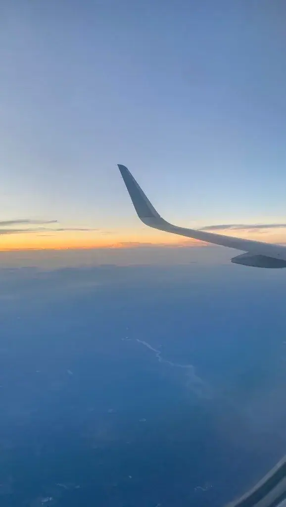 Airplane wing above clouds at sunset