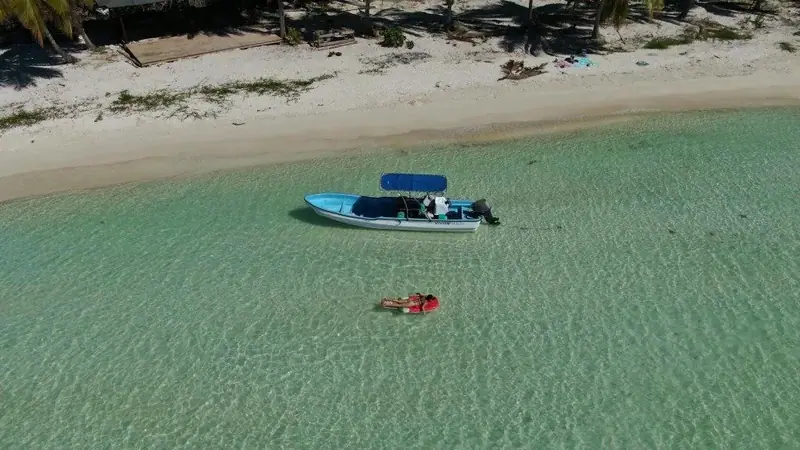 Aerial view of a boat and swimmer in clear turquoise water