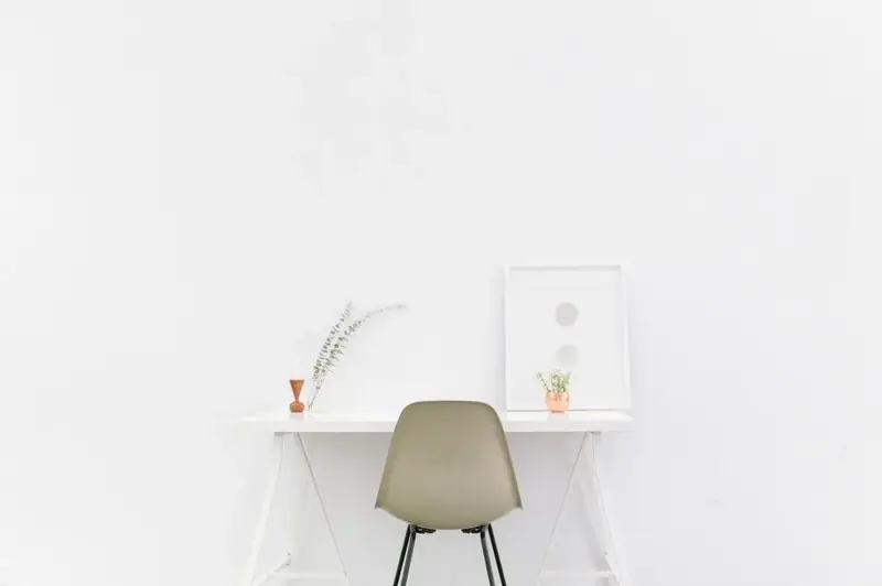 Minimal white desk with a chair, small plants, and framed art