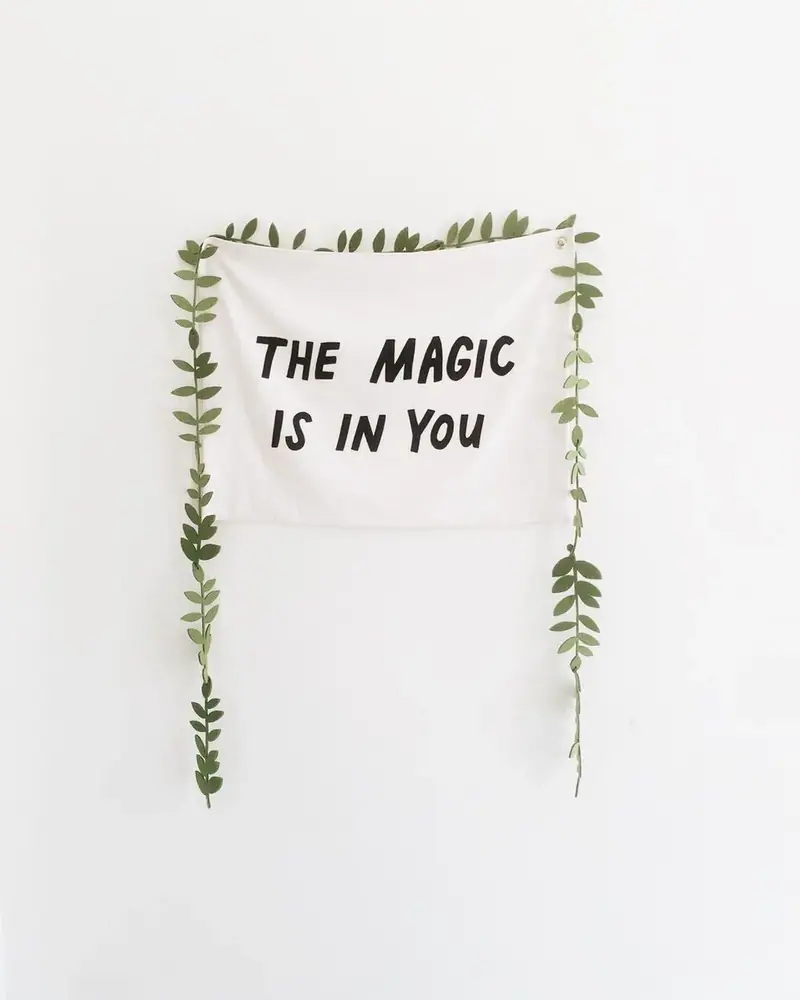 Wall hanging reading “The magic is in you” framed by vines
