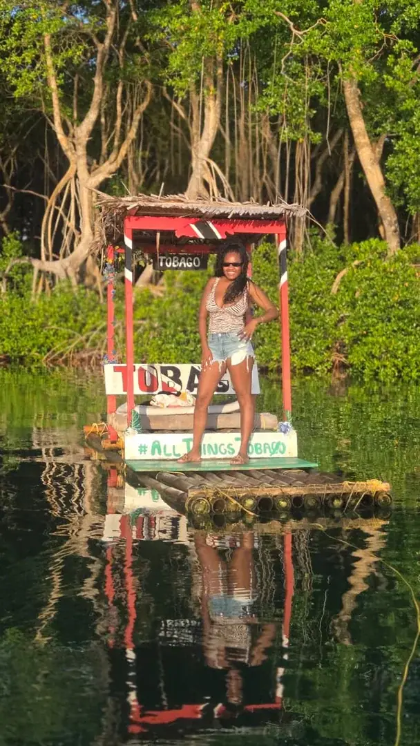 Leslieann standing on a bamboo raft surrounded by mangroves and reflected in the water