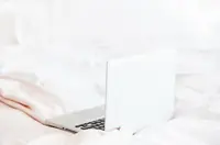A laptop resting on soft white bedding