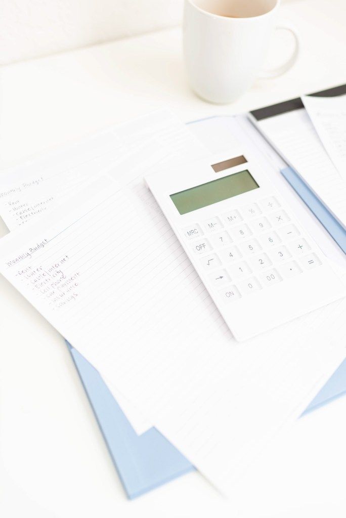 Calculator and financial papers beside a cup of coffee