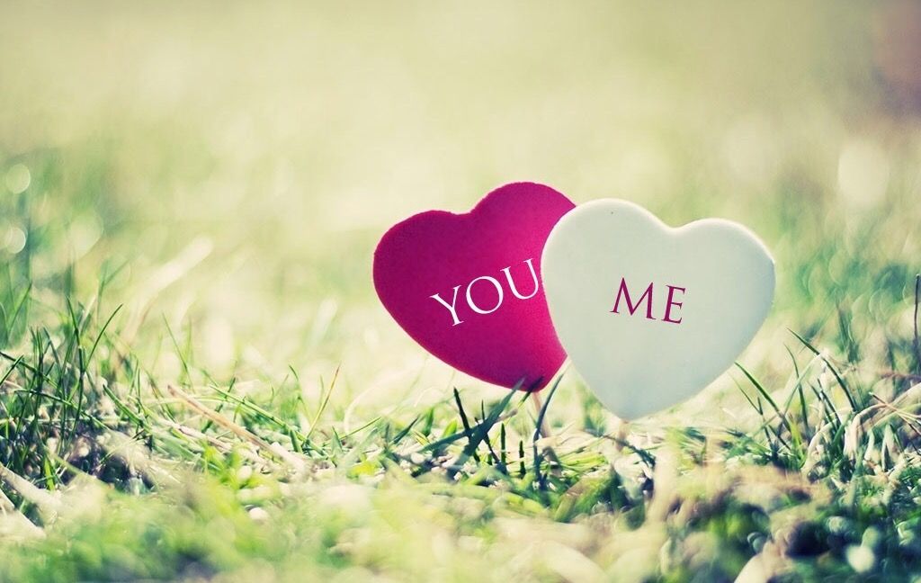 Two heart-shaped notes reading “You” and “Me” in grass