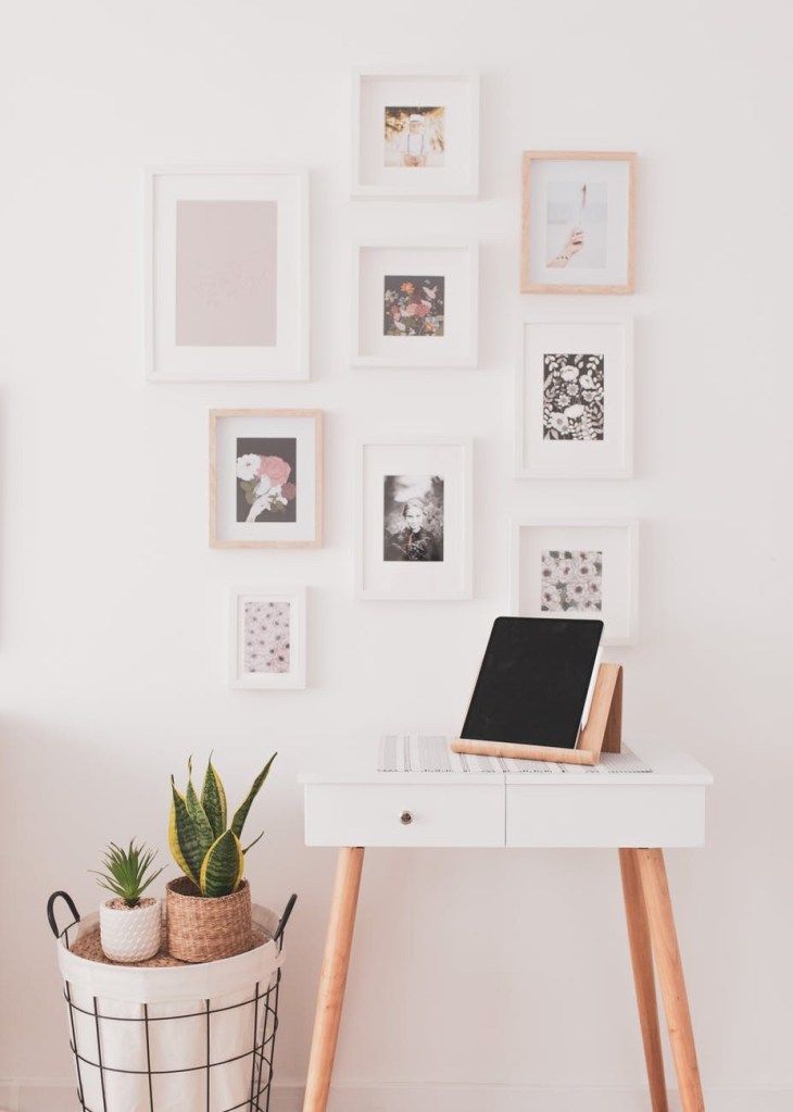 Minimal white desk with laptop, wall art, and plants