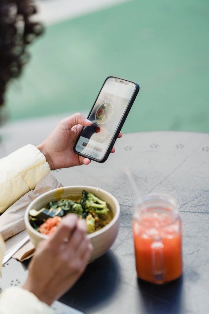 Person eating a salad while looking at a smartphone