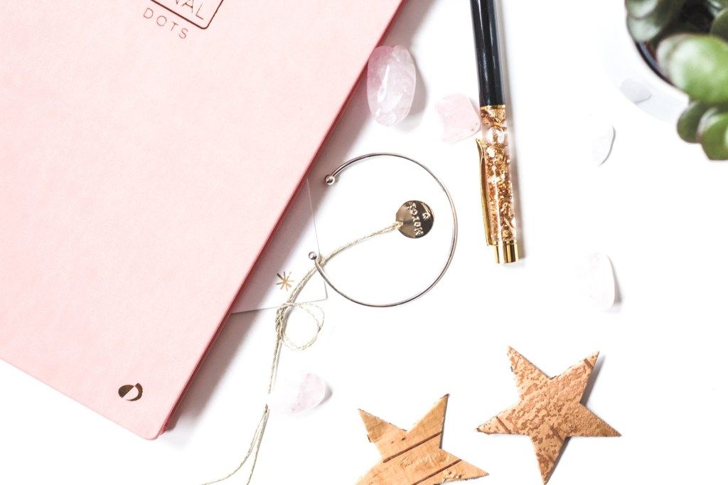 Pink notebook, pen, glasses, and wooden star ornaments
