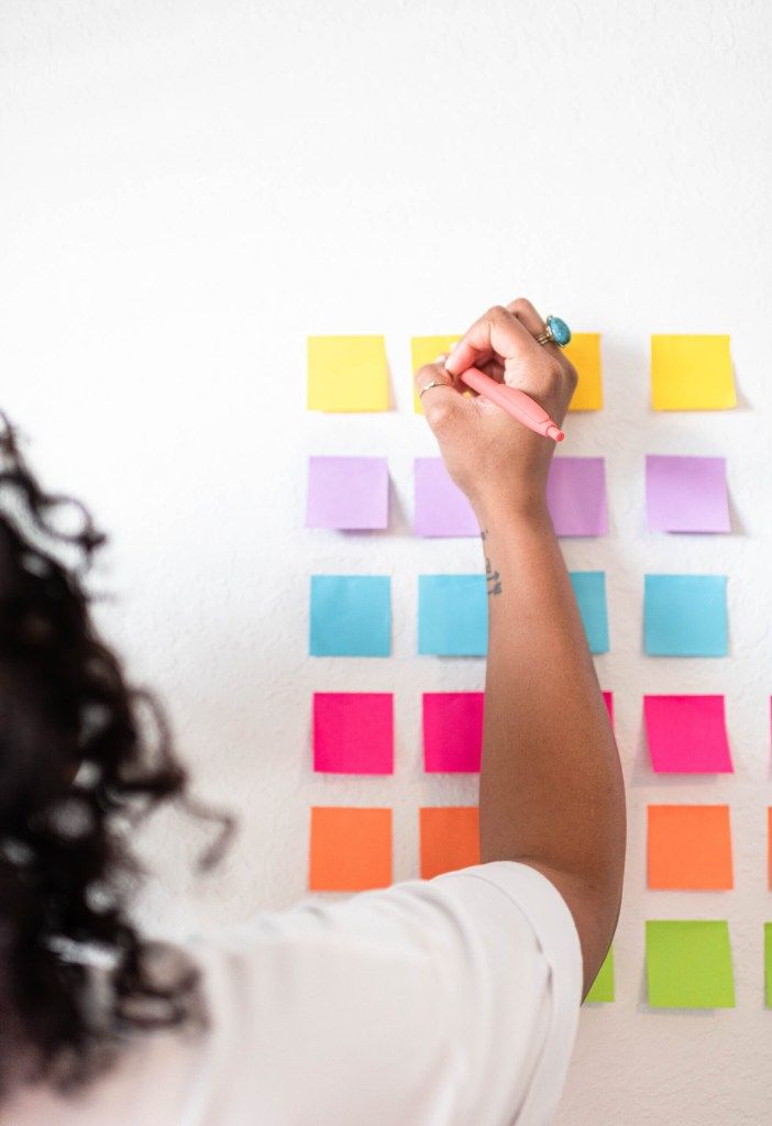 Person placing colorful sticky notes on a wall