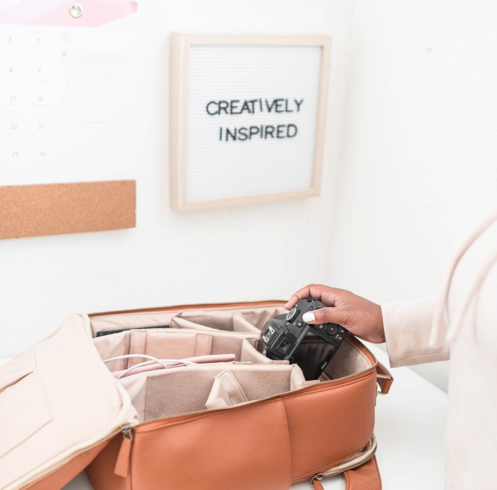 Camera in an open bag beneath a sign reading “Creatively Inspired”