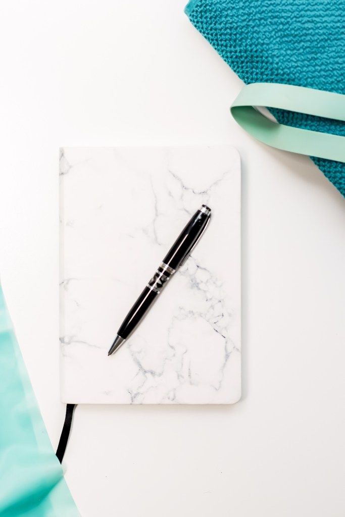 Marble notebook and pen beside a turquoise towel