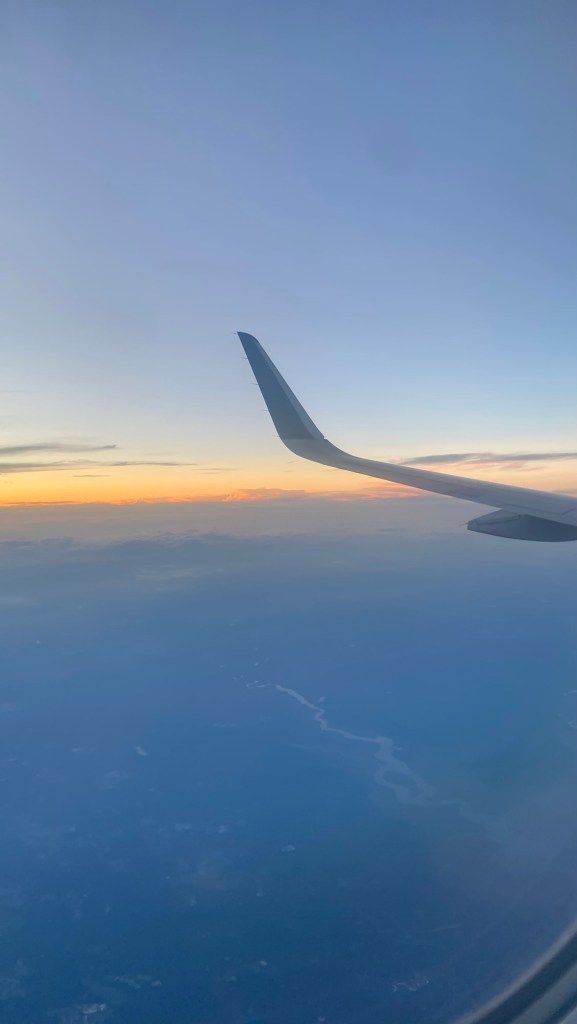 Airplane wing above clouds at sunset