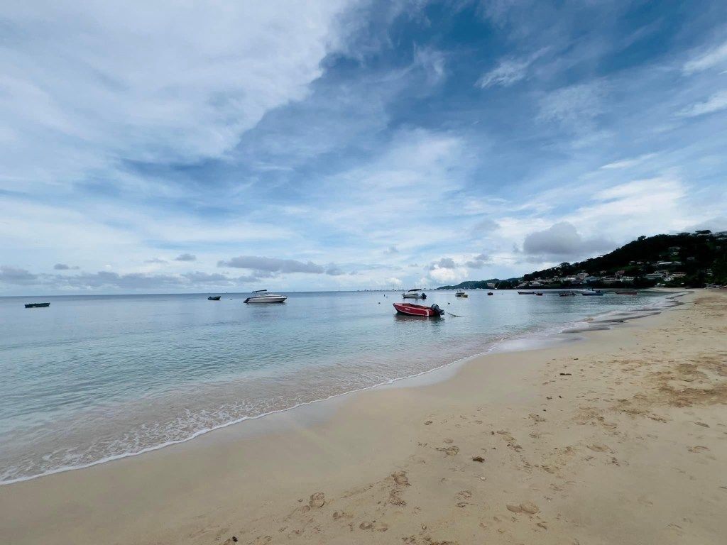 Quiet sandy beach with small boats floating offshore