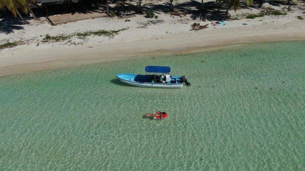 Aerial view of a boat and swimmer in clear turquoise water
