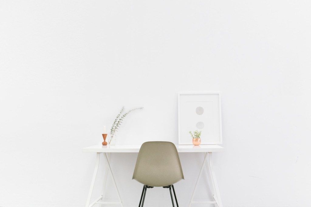 Minimal white desk with a chair, small plants, and framed art