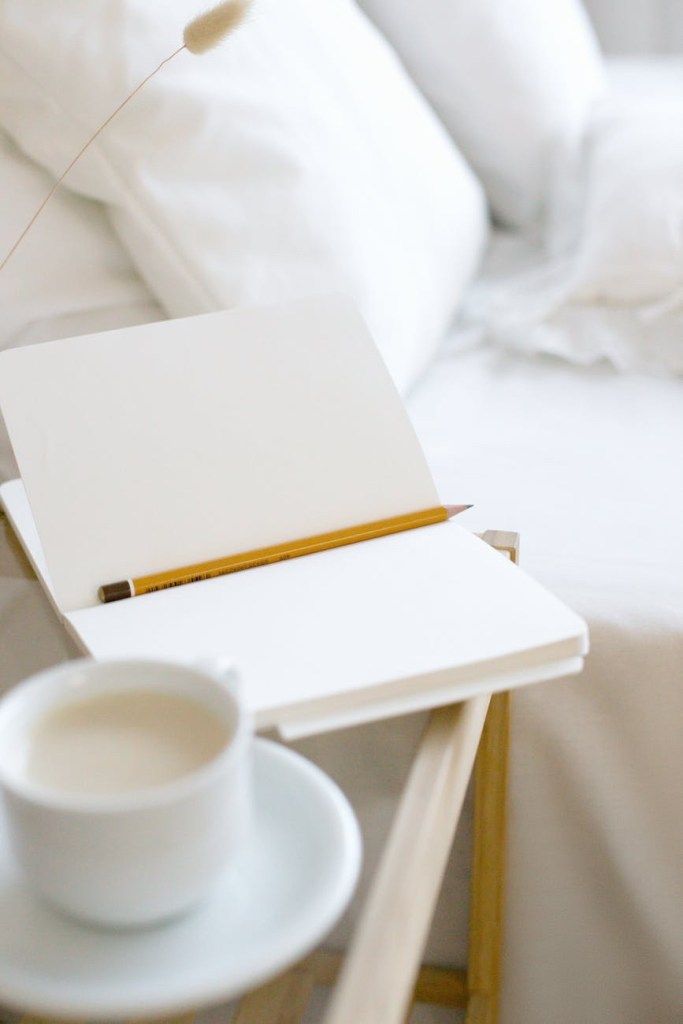 Blank notebook and pencil beside a cup of coffee