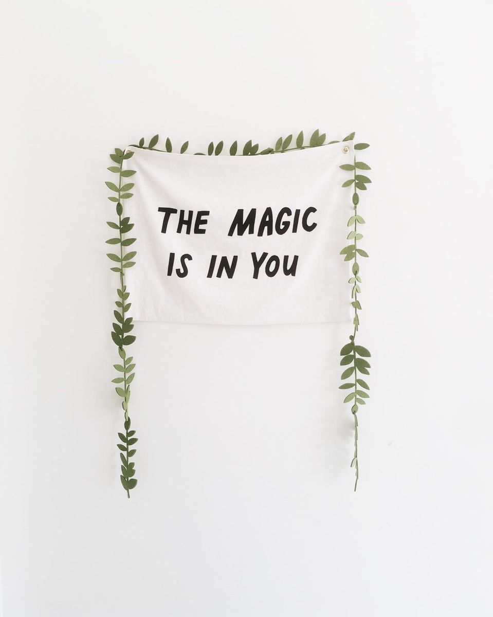 Wall hanging reading “The magic is in you” framed by vines
